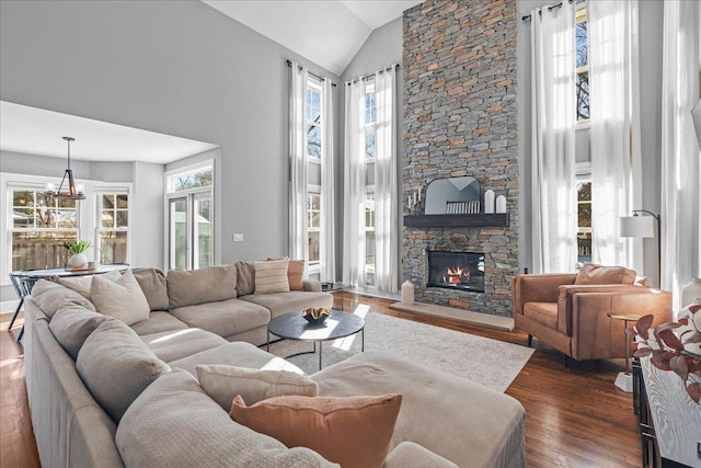 living room with dark wood-style floors, a notable chandelier, a fireplace, and high vaulted ceiling