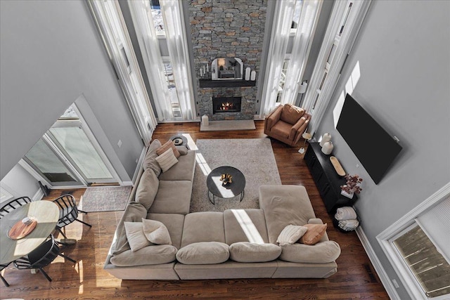 living room with a healthy amount of sunlight, dark wood finished floors, and a stone fireplace