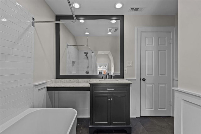 bathroom featuring vanity, walk in shower, a freestanding tub, and visible vents