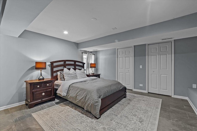 bedroom featuring two closets, visible vents, and baseboards