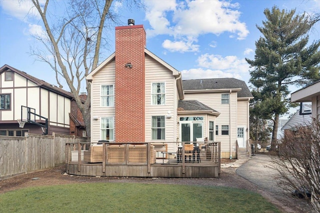 rear view of property with a lawn, a chimney, a wooden deck, and fence