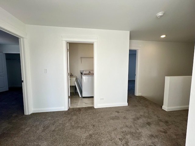 unfurnished bedroom with washer / clothes dryer, sink, a spacious closet, and dark colored carpet