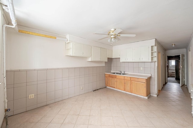 kitchen featuring ceiling fan, sink, and tile walls