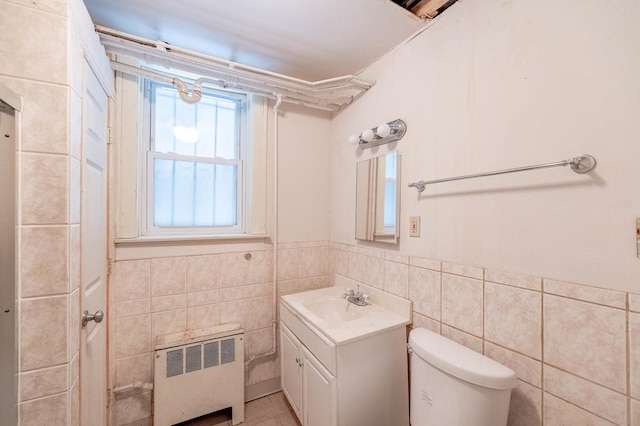 bathroom with radiator heating unit, toilet, tile walls, and vanity