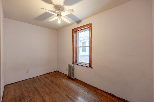 empty room with ceiling fan, radiator heating unit, and wood-type flooring