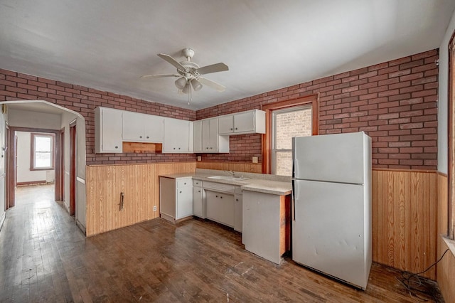 kitchen featuring brick wall, white cabinetry, and fridge