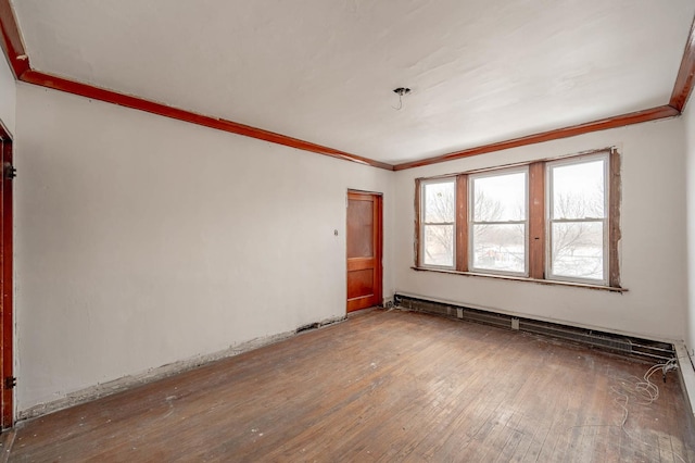 spare room featuring hardwood / wood-style floors, ornamental molding, and a baseboard heating unit