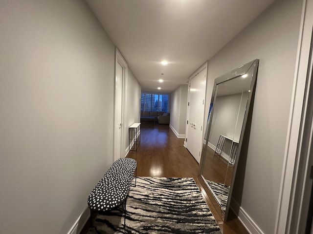 hallway featuring dark wood-type flooring and baseboards