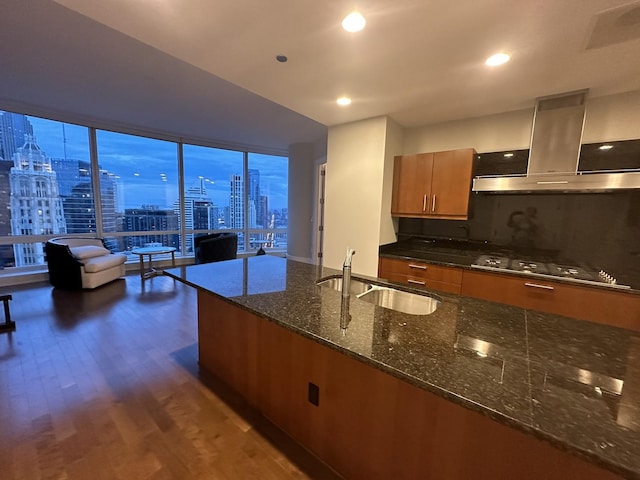 kitchen with dark stone countertops, a view of city, island exhaust hood, gas stovetop, and a sink