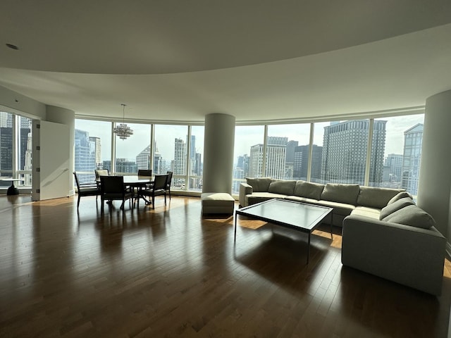 living area featuring dark wood-style floors, a chandelier, and a city view