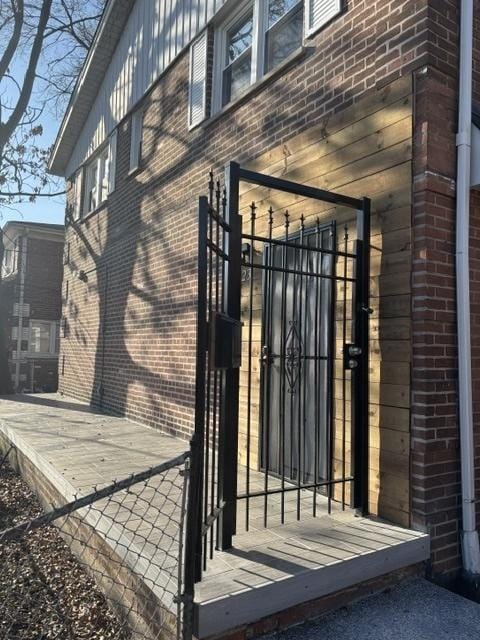 exterior space featuring a gate, fence, and brick siding