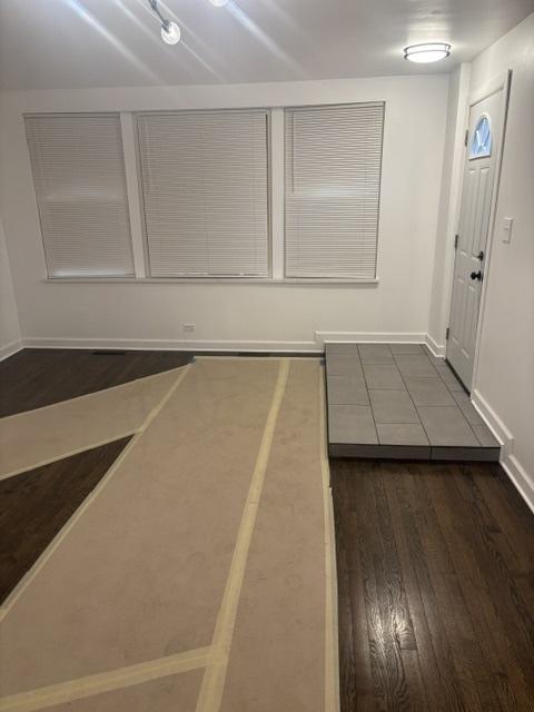 foyer entrance with dark wood-style floors and baseboards