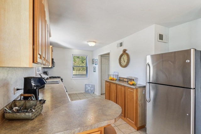 kitchen featuring stainless steel refrigerator, sink, and light tile patterned floors