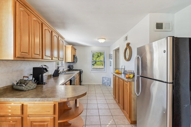 kitchen featuring sink, light tile patterned floors, stainless steel fridge, and range with gas stovetop