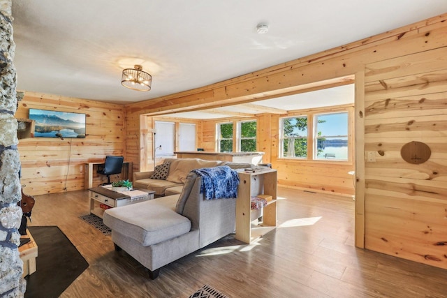 living room featuring an inviting chandelier, hardwood / wood-style floors, and wood walls