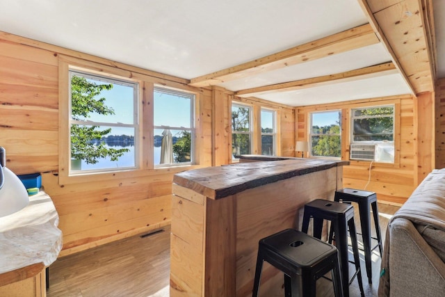 bar with a water view, wood-type flooring, wooden walls, and butcher block counters