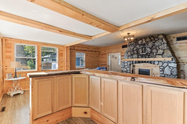 kitchen featuring light brown cabinetry, wood walls, light wood-type flooring, kitchen peninsula, and beamed ceiling