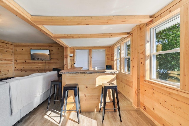 bar featuring beamed ceiling, light hardwood / wood-style floors, and wood walls