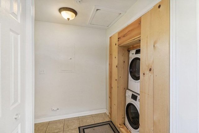 clothes washing area with stacked washer / drying machine and light tile patterned floors