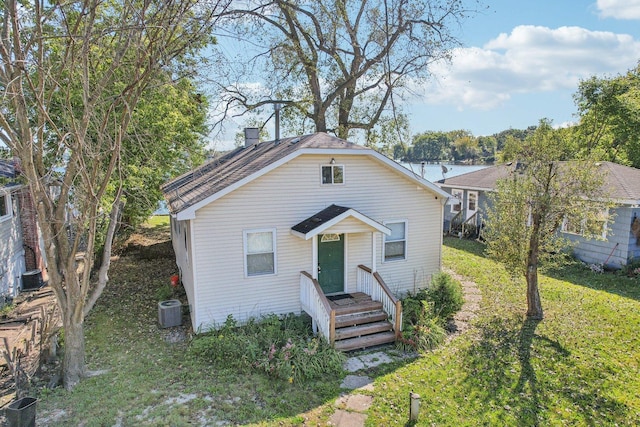 bungalow-style home with central AC unit and a front yard