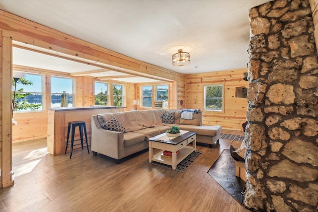 living room with a water view, dark wood-type flooring, a chandelier, and wooden walls