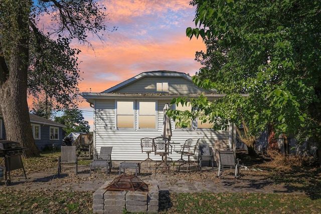 back house at dusk featuring a patio area and an outdoor fire pit