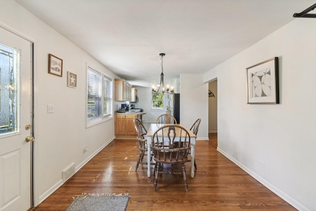 dining space featuring dark hardwood / wood-style floors and a chandelier