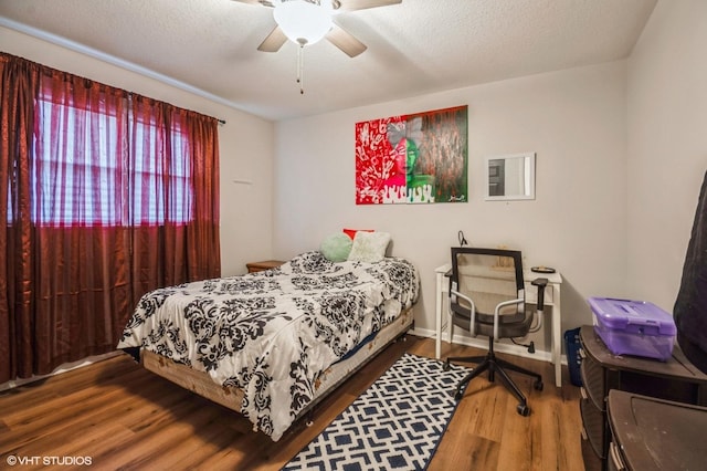 bedroom featuring a textured ceiling, wood finished floors, a ceiling fan, and baseboards