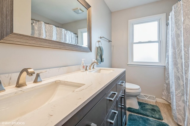 bathroom with a wealth of natural light, visible vents, a sink, and toilet