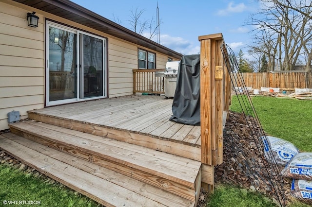 wooden deck with a lawn, fence, and a grill