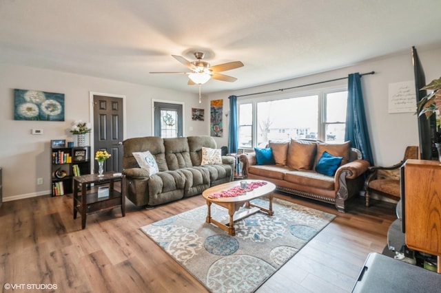 living area featuring light wood finished floors, ceiling fan, and baseboards