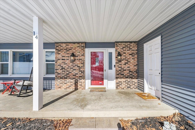 property entrance featuring covered porch and brick siding