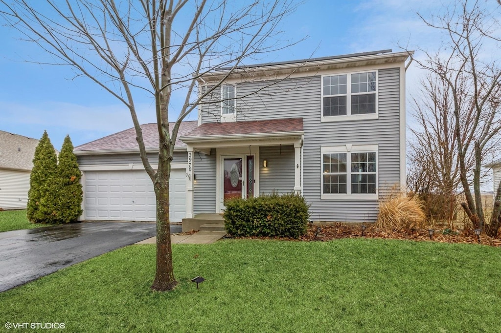 traditional-style house with driveway, a garage, and a front lawn