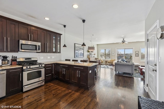 kitchen featuring a peninsula, dark wood-style floors, stainless steel appliances, and dark brown cabinets