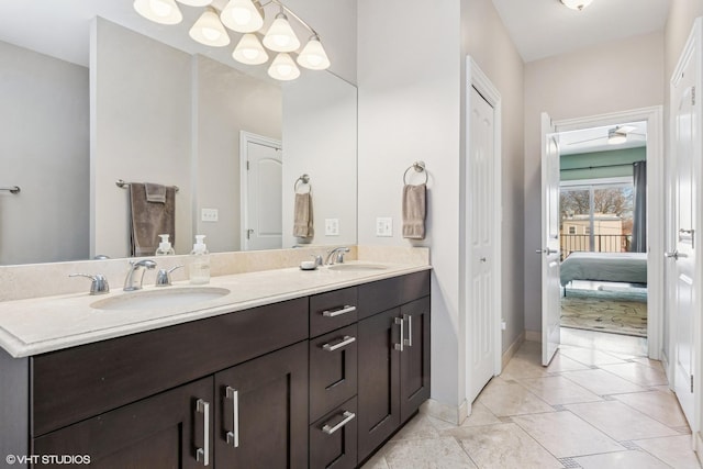 ensuite bathroom featuring connected bathroom, a sink, baseboards, and double vanity