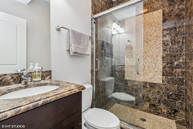 bathroom with a stall shower, vanity, and toilet