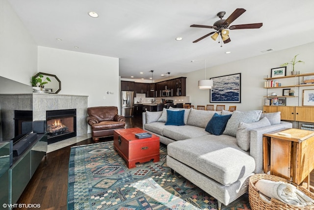 living room with dark wood finished floors, recessed lighting, visible vents, a premium fireplace, and ceiling fan