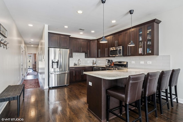 kitchen with a peninsula, dark brown cabinetry, stainless steel appliances, and a sink