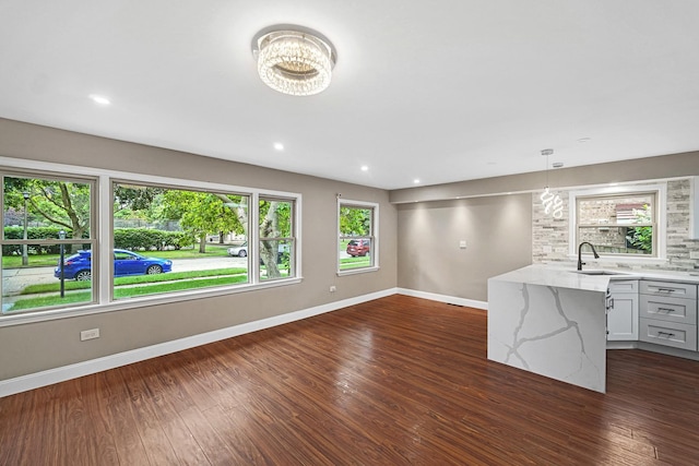 unfurnished living room with dark hardwood / wood-style floors, a chandelier, and sink