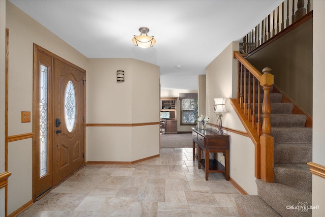 foyer entrance featuring stone finish flooring, stairs, and baseboards