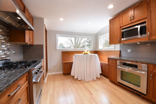 kitchen with stainless steel appliances, light wood-type flooring, brown cabinets, and under cabinet range hood