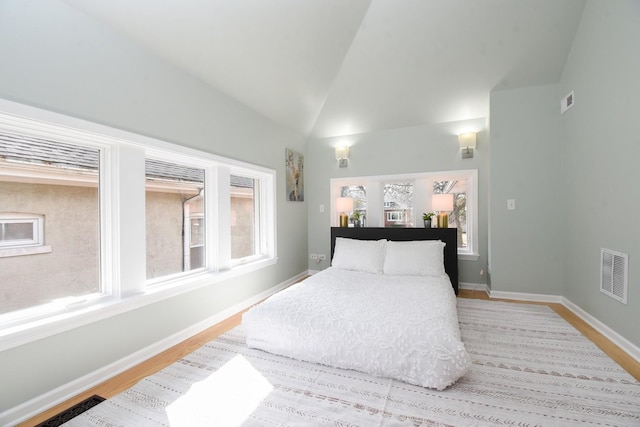 bedroom featuring high vaulted ceiling, visible vents, light wood finished floors, and baseboards