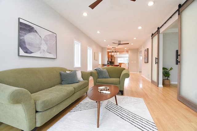 living room featuring recessed lighting, ceiling fan, light wood finished floors, and a barn door