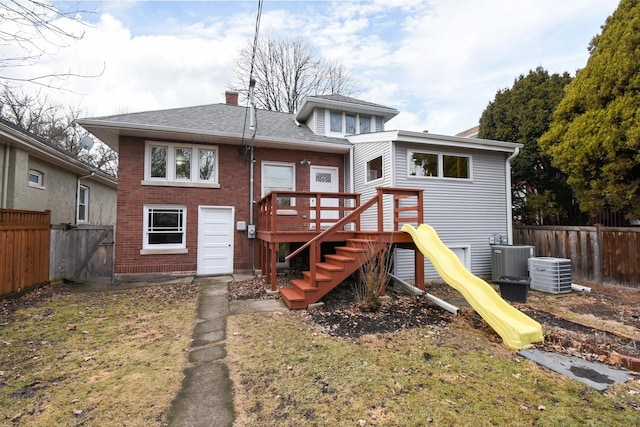 back of property with cooling unit, a fenced backyard, brick siding, and a chimney