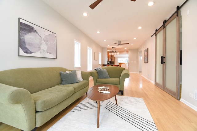 living area with a barn door, recessed lighting, a ceiling fan, baseboards, and light wood-type flooring