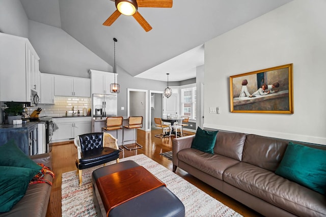 living room with wood-type flooring, vaulted ceiling, sink, and ceiling fan