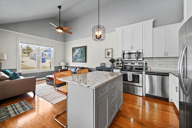 kitchen with a center island, appliances with stainless steel finishes, light stone countertops, and white cabinets