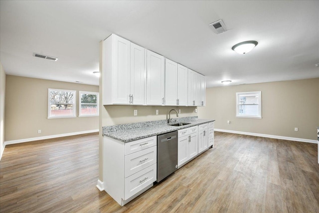 kitchen with dishwasher, sink, white cabinets, light stone counters, and light wood-type flooring