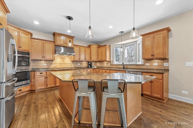 kitchen featuring stainless steel appliances, dark wood-style flooring, a kitchen island, a sink, and range hood