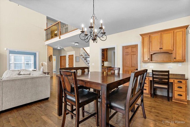 dining area featuring dark wood-style flooring, stairway, and an inviting chandelier